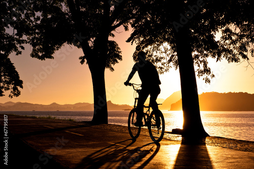 Fototapeta Silhouette of a Man Cycling during Beautiful Sunrise