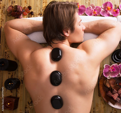 Poster, Tablou Man having stone massage in spa salon.