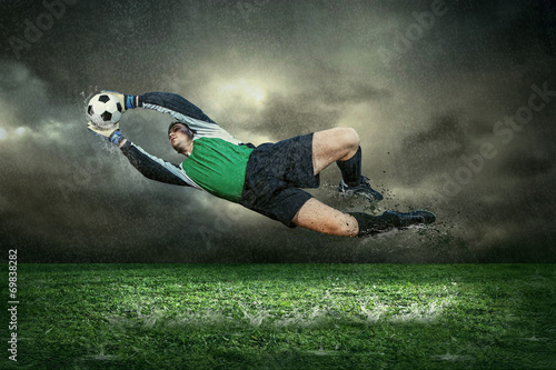 gracz-futbolu-z-pilka-w-akci-pod-deszczem-outdoors