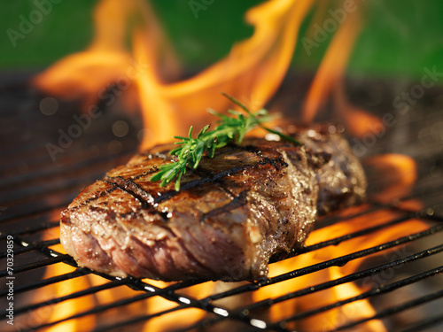 Zdjęcia steak with flames on grill with rosemary