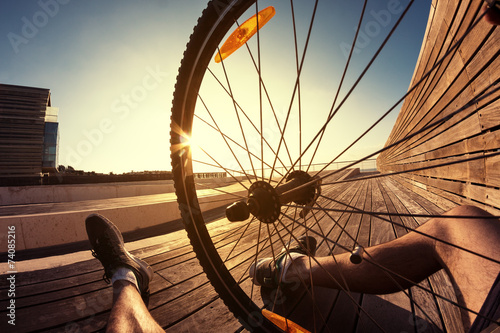 Fototapeta cyclist sitting with wheel of mountain bike, POV view