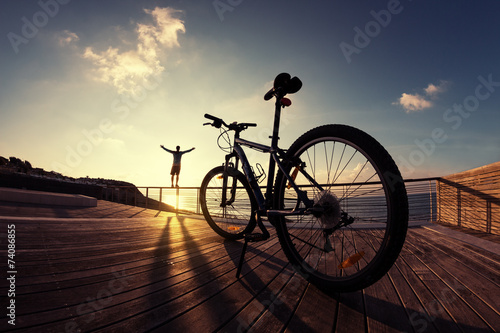 Fototapeta silhouette of sportsman and mountain bike at the sunset
