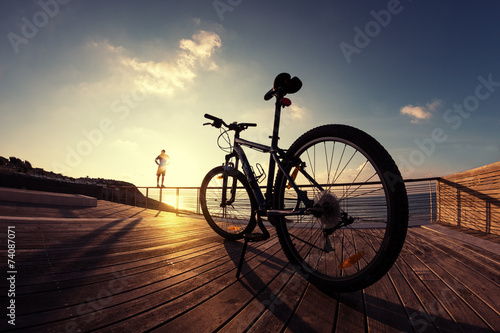 Fototapeta silhouette of sportsman and mountain bike at the sunset