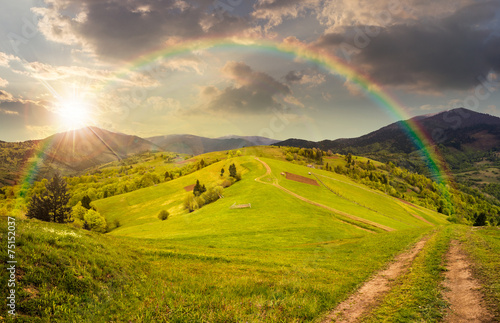 fence on hillside meadow in mountain at sunset
