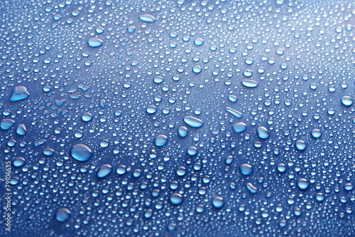 Fototapeta Water drops on glass on blue background