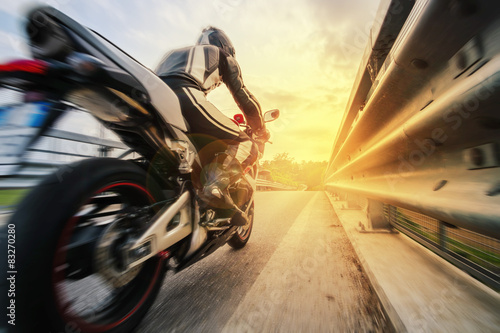 Moto da strada sfreccia vicino al guard rail al tramonto