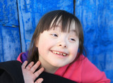 Young girl smiling on background of the blue wall.
