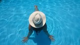 Mujer con sombrero relajada en la piscina