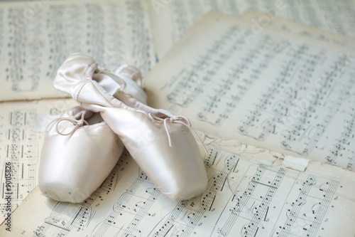 Poster Ballet shoes laying on the old piano musical notes