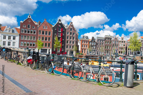 Poster Amsterdam, the Netherlands-April 27: Amsterdam cityscape with apartment houses and bikes parked on the bridge on April 27,2015