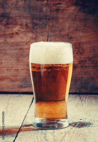large glass of light beer with foam on the old wooden background Poster