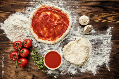 Poster Pizza dough with ingredients on wood