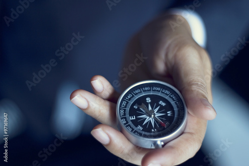 Businessman with a compass holding in hand, color tone film look плакат