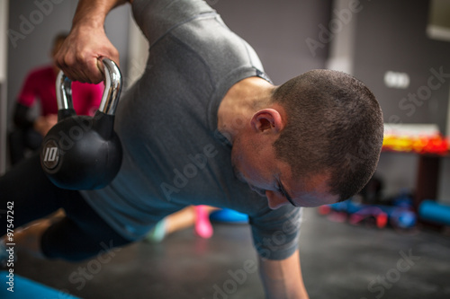 Zdjęcia Young man lifting dumbbell and kettlebell at the fitness center