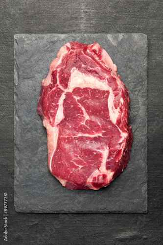 Zdjęcia Raw ribeye steak on a slate board. Top view
