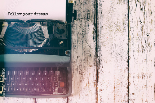 Poster abstract vintage filtered image of top view photo of vintage typewriter with the phrase: follow your dreams, on wooden table