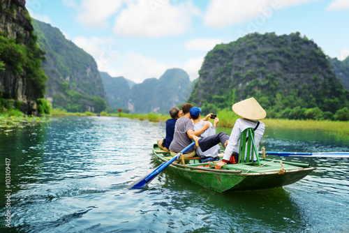 Poster, Tablou Tourists taking picture. Rower using her feet to propel oars