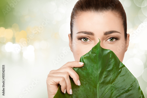 Poster, Tablou Gorgeous young woman with a fresh leaf to her face