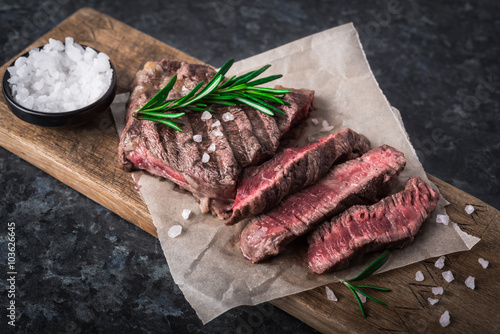 Zdjęcia Grilled beef steak with rosemary and salt on cutting board