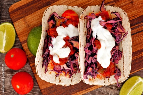 Vászonkép Two spicy fish tacos with red cabbage lime slaw, salsa and sour cream, downward