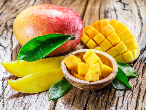 Mango fruit and mango cubes on the wooden table.
