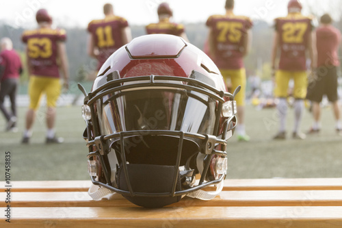 futbol-amerykanski-helm-na-lawce-i-druzyna-w-tle