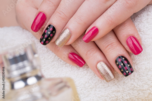 Manicure - Beauty treatment photo of nice manicured woman fingernails. Very nice feminine nail art with nice pink, gold and black nail polish. © tamara83