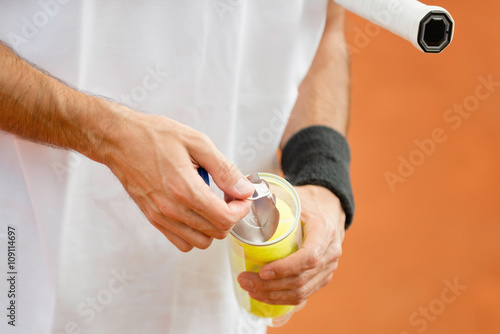 New balls. Tennis player opening can with new tennis balls