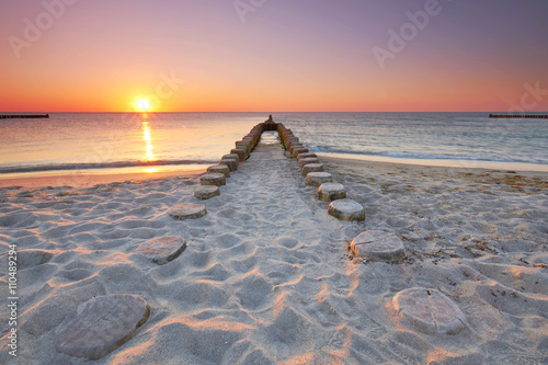 lange hölzerne Buhnen am Strand, Sonnenuntergang am Meer
