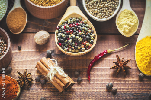 Beautiful colorful spices in wooden spoons and bowls on an old wooden brown table Poster