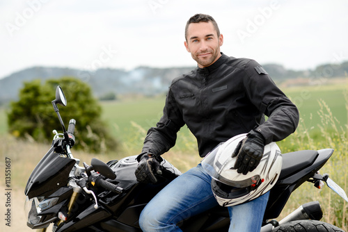 handsome young man biker with white helmet riding black motorcycle