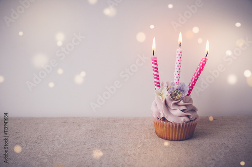Poster Pink and purple Birthday cupcake with three candles, fairy light toning backgrou