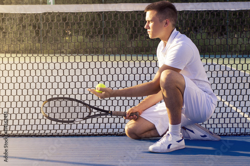 Le joueur de tennis à genoux dans la police de la raquette de tenue nette et la