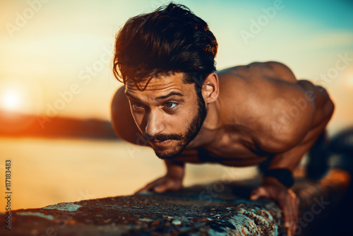 Zdjęcia Young athletic man doing push ups outdoors