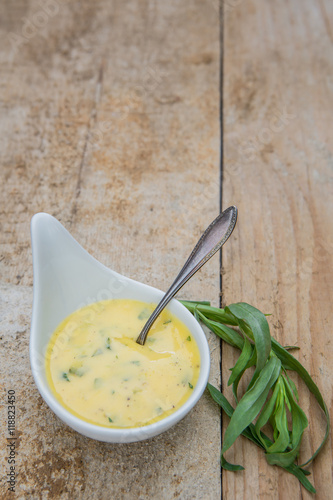 Schale mit Sauce Béarnaise, Estragon und einem Löffel auf einem alten Holzuntergrund