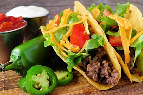 Hard shelled tacos with ground beef, lettuce, tomatoes and cheese close up, on r Plakát