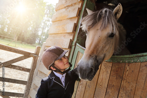 Poster jeune fille 11 ans en tenue d'équitation dans écurie, box avec cheval