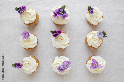 Poster Rose flower frosting vanilla cupcakes with purple edible flowers
