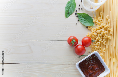 spaghetti with ingredients for cooking on wood background