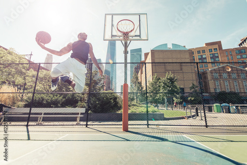 Poster Street basketball athlete performing huge slam dunk on the court