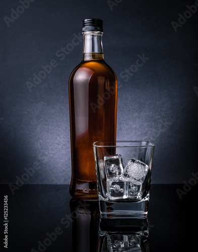 whisky-z-kostkami-lodu-w-szklanej-pobliskiej-butelce-na-czerni