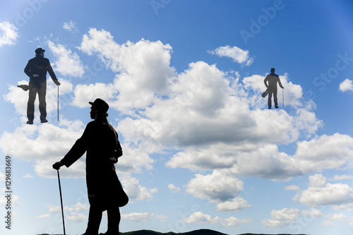 Poster Surrealistic image of silhouettes of men with a cane and bowl hat climbing up th