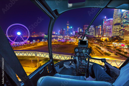 Poster Helicopter cockpit aerial view of cityscape in Hong Kong, Central District, with Observation Ferris Wheel at Victoria Harbour illuminated at night