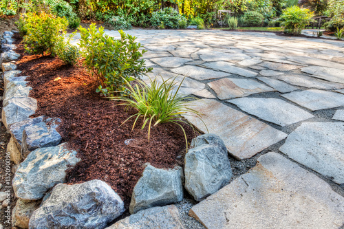 Completed flower beds around new stone patio with plants in place