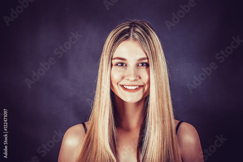 Poster Beautiful young blonde woman with long straight hair on a dark background