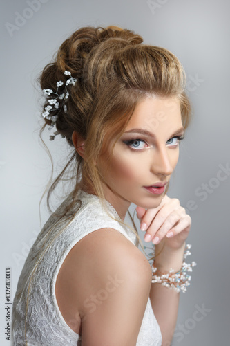 Pretty bride with beautiful elegant hairstyle, isolated on a gray background. © ksi