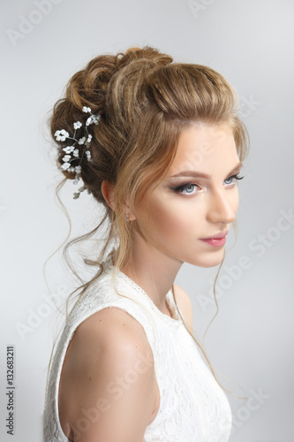 Pretty bride with beautiful elegant hairstyle, isolated on a gray background. © ksi