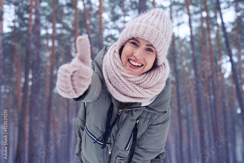 Cheerful young woman holding thumb up showing approval