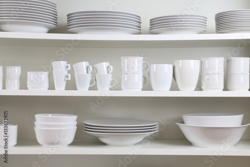 white dishes on a white shelf © monropic
