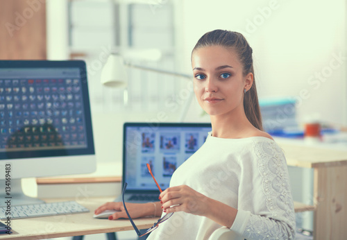 Young woman working in office, sitting at desk